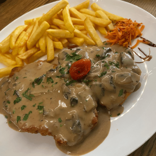 Schnitzel mit einer Sauce und Pommes frites