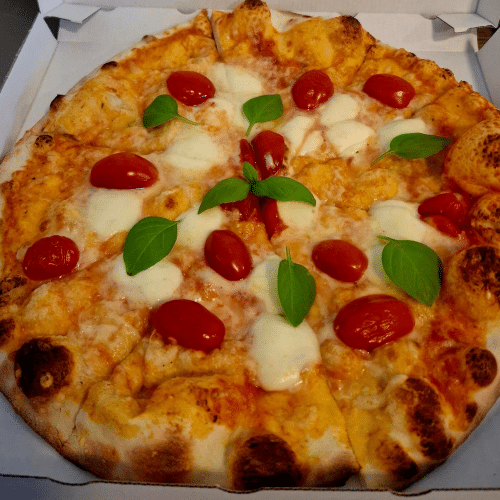 Pizza mit Mozzarella, frischen Tomaten und frischem Basilikum