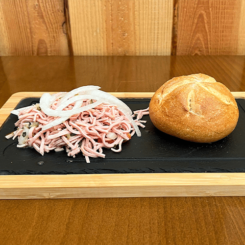 Hausgemachter Wurstsalat mit Brötchen und frischen Zwiebeln